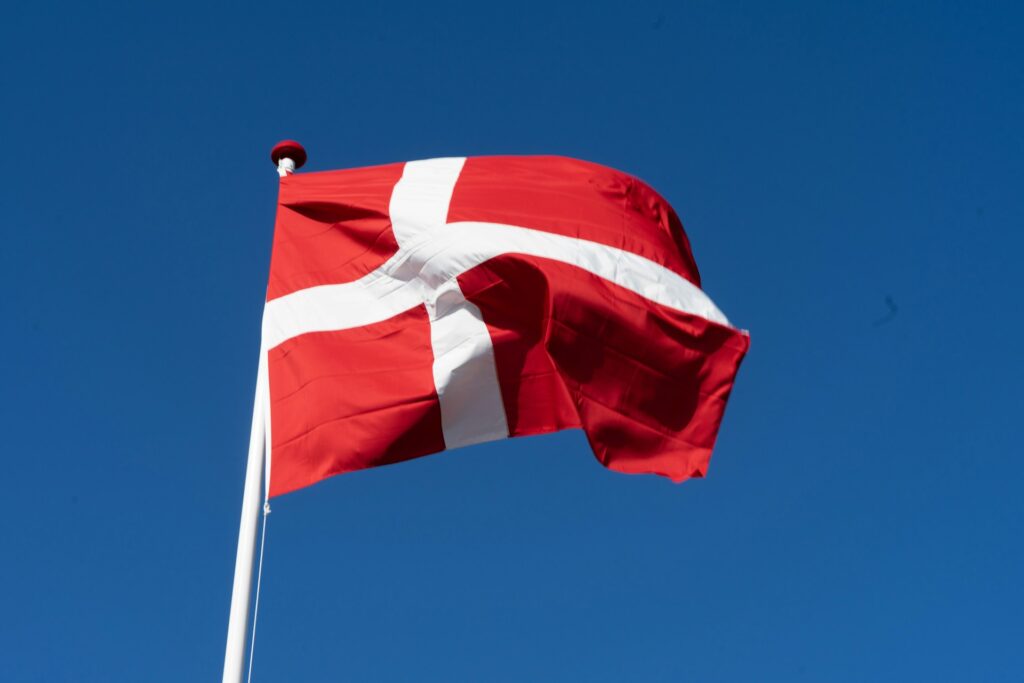 Dannebrog flag mod blå himmel – Newsec skaber tryghed og styring for danske foreninger