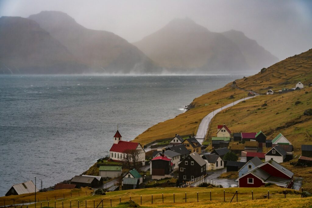 Landsby ved havet med små huse og kirke, symbol på dansk fællesskab og ejendomsadministration