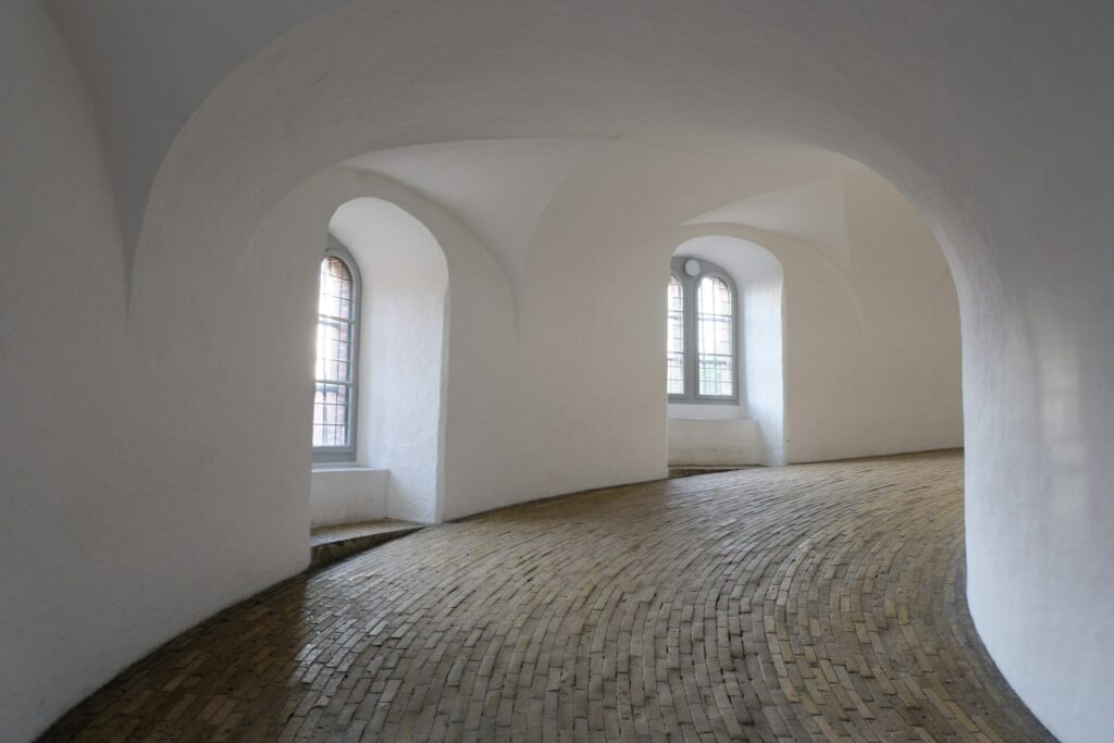Indre af Rundetårn med hvidkalkede vægge og buede vinduer, symbol på kultur, fællesskab og ejendomsadministration