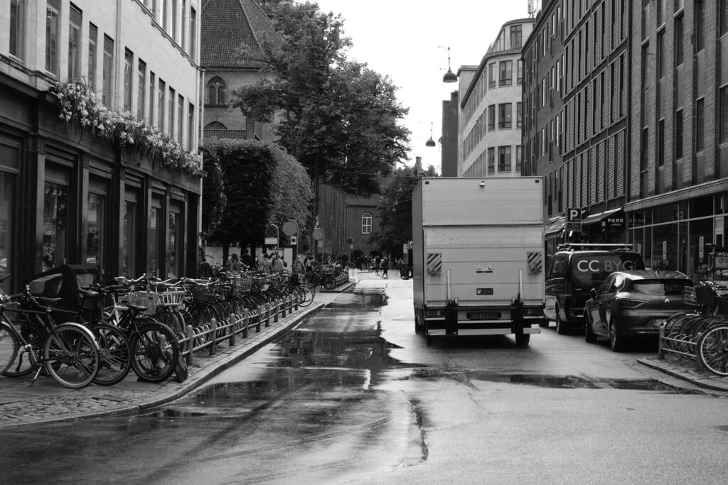 Black and white photo of Copenhagen street with bicycles, cars, and delivery truck – Newsec association advisory