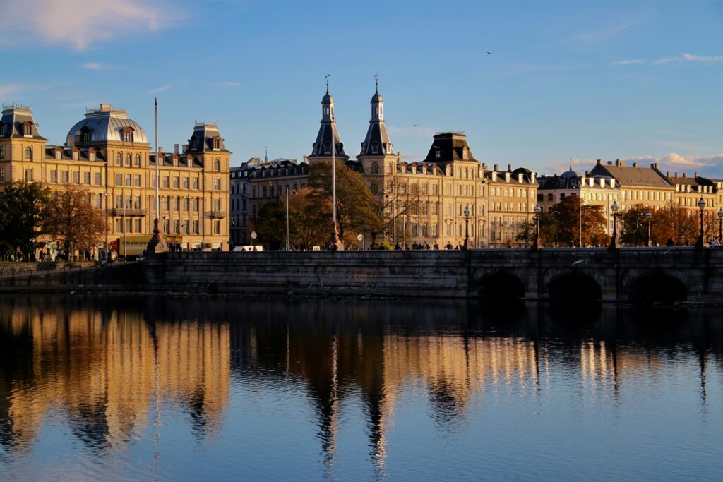 Historiske boligejendomme ved søerne i København ved solnedgang, spejlet i vandet – et symbol på forandring og tradition.