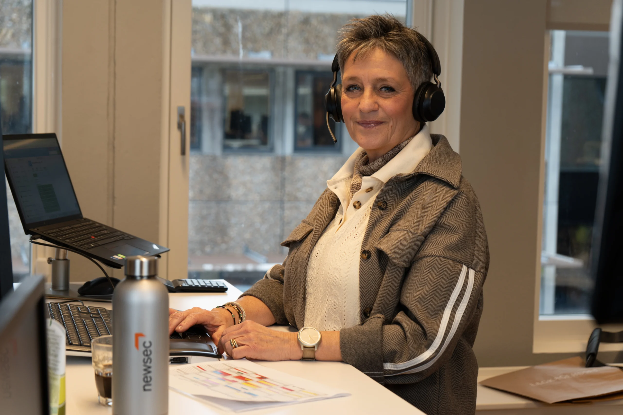 Ejendomsadministrator hos Newsec arbejder ved skrivebord med headset og sikrer professionel ejendomsadministration for boligforening