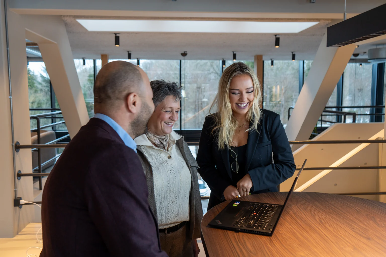 Tre Newsec-medarbejdere står ved laptop og samarbejder om ejendomsadministration og professionel foreningsadministration i Aarhus